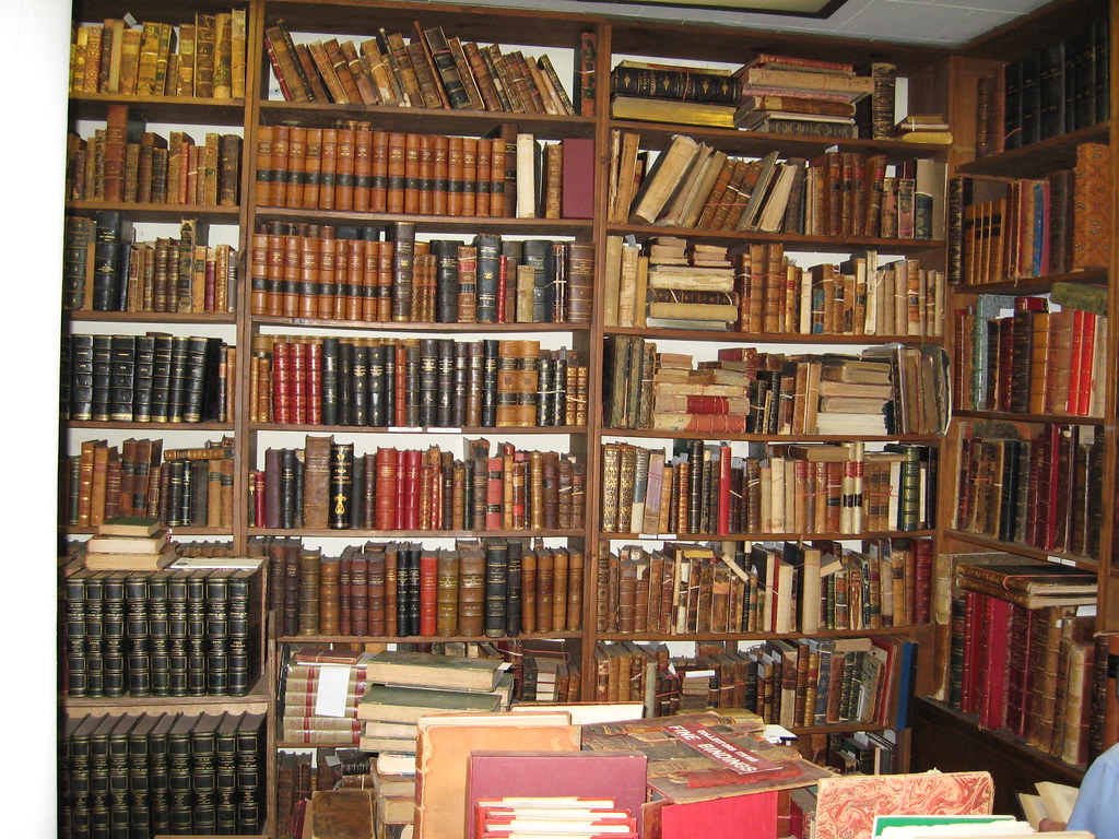 a distance shot of a large bookshelf holding older looking books